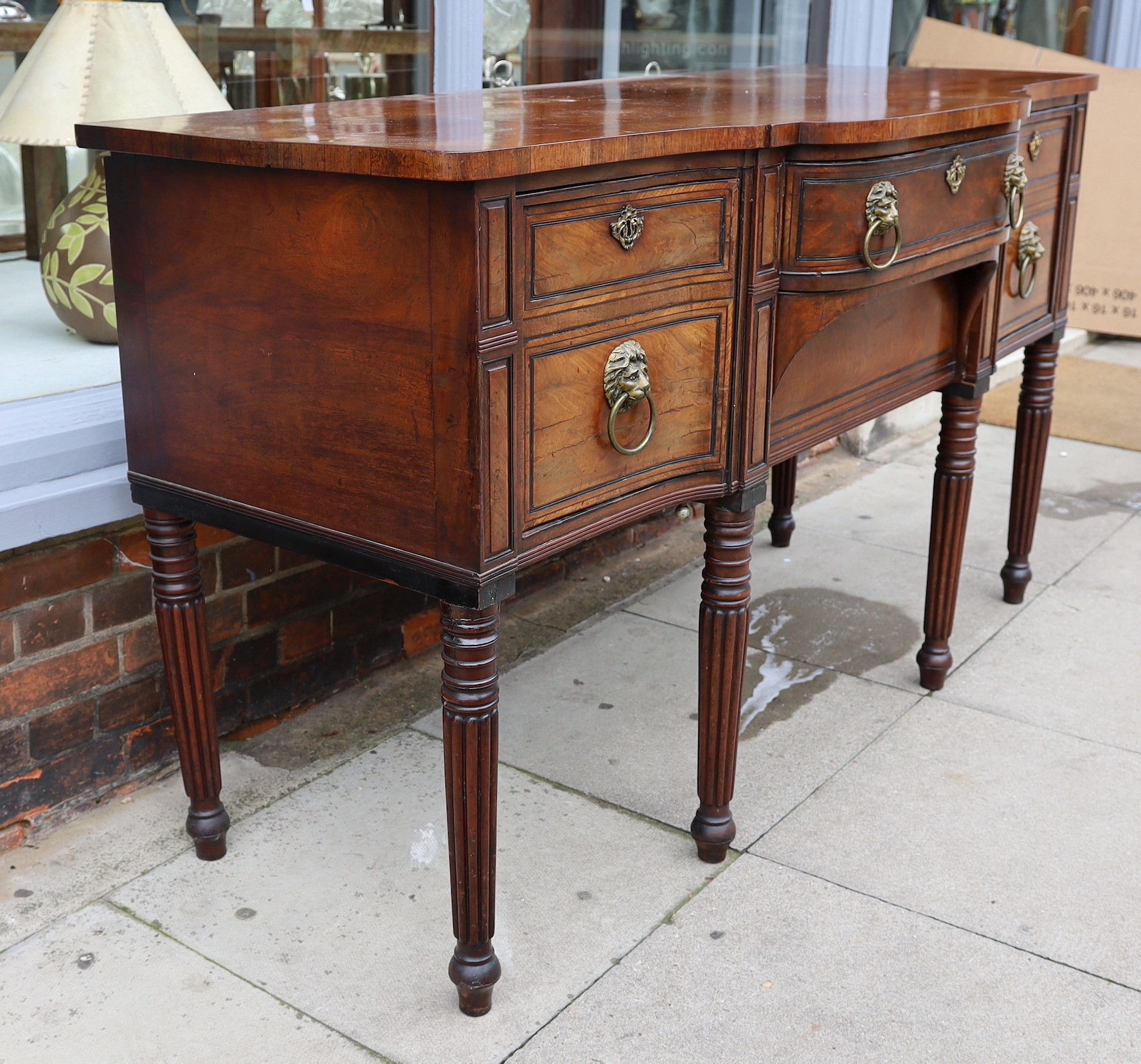 A Regency ebony strung mahogany breakfront sideboard, each deep drawer with ‘secret’ revolving cellaret compartment, centred with two long drawers, on ring turned fluted and tapered legs, width 167cm. depth 69cm. height